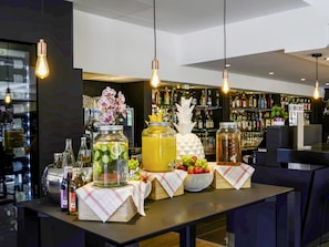 A bar area with a counter, hanging light bulbs, and a 'Bienvenue' sign. - Novotel Dijon Sud (Marsannay-la-Cote)