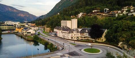 A riverside town with a hotel, a roundabout, and a mountain backdrop.