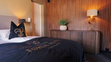 Una habitación de hotel con una cama, una mesita de noche, una lámpara y una pared con paneles de madera vertical.