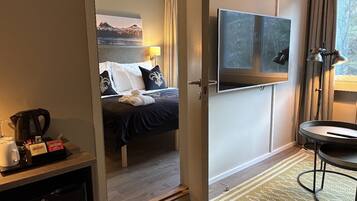 A hotel room with a bed, a TV, a coffee station, and a view of a mountain.