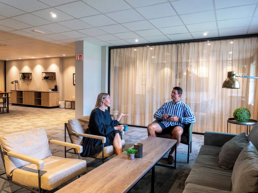 Ein stilvoller Lounge-Bereich mit Sitzgelegenheiten, einem Couchtisch und einem kleinen Beistelltisch mit einer Pflanze.