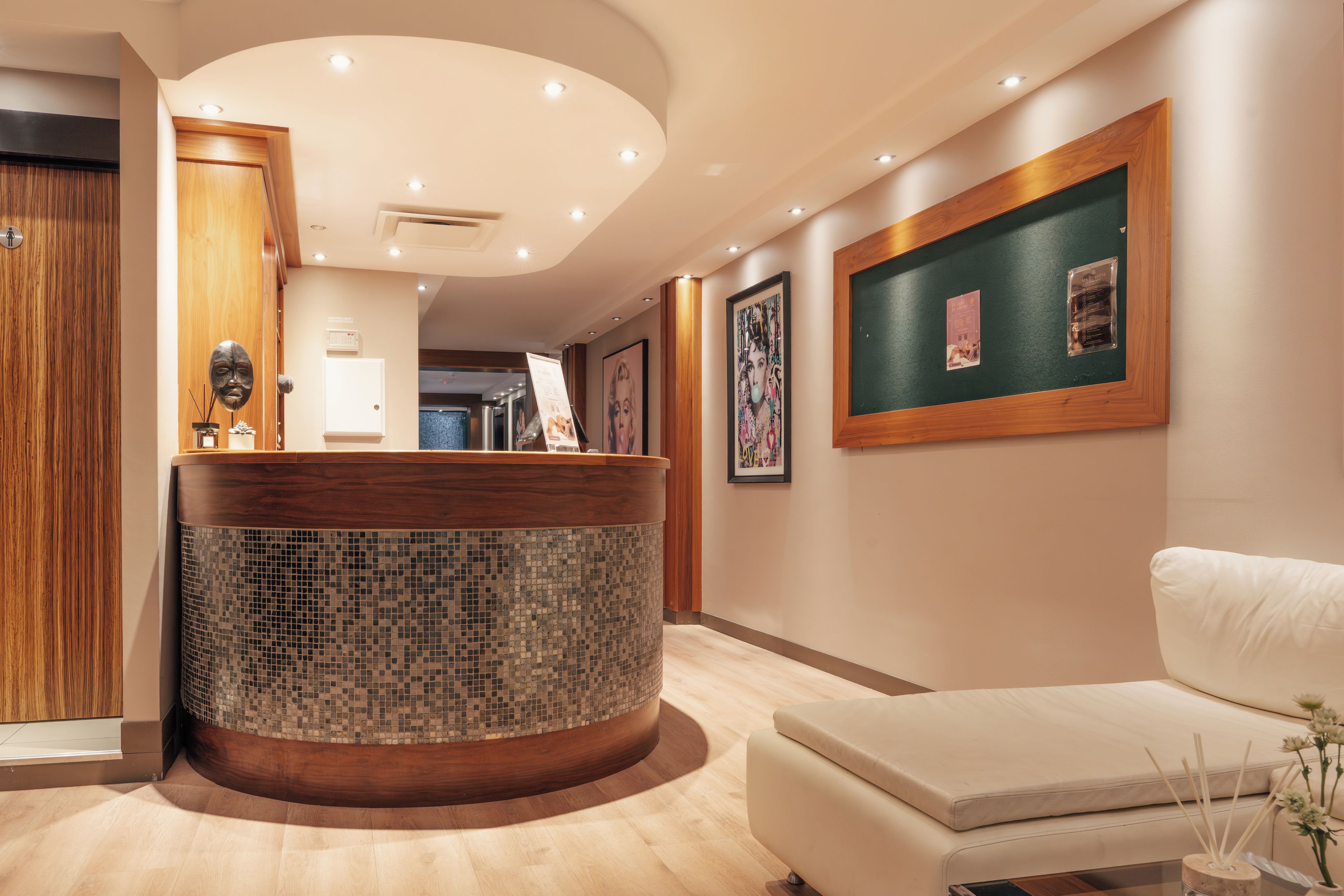 A reception area with a wooden reception desk, a white sofa, and framed artwork on the walls.