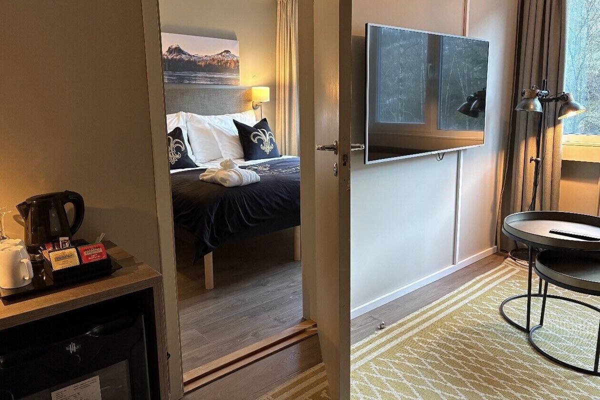Habitación de hotel con cama, televisor, estación de café y vista a una montaña.