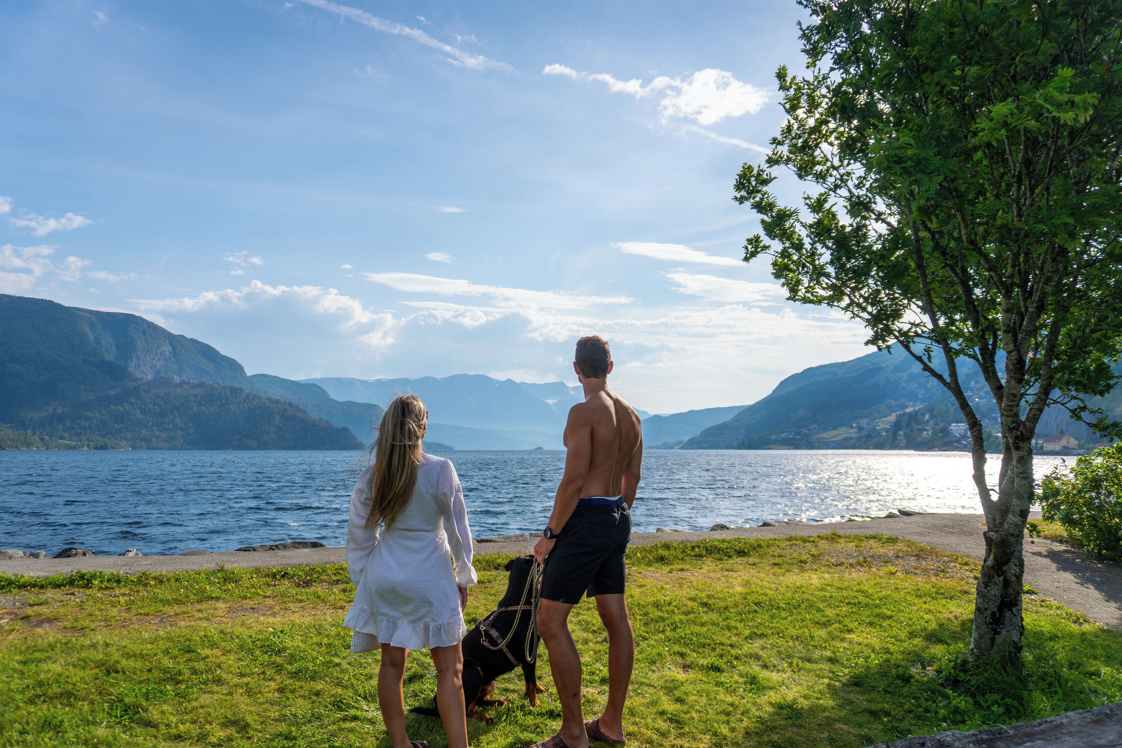 A couple standing by a lake with mountains in the background.