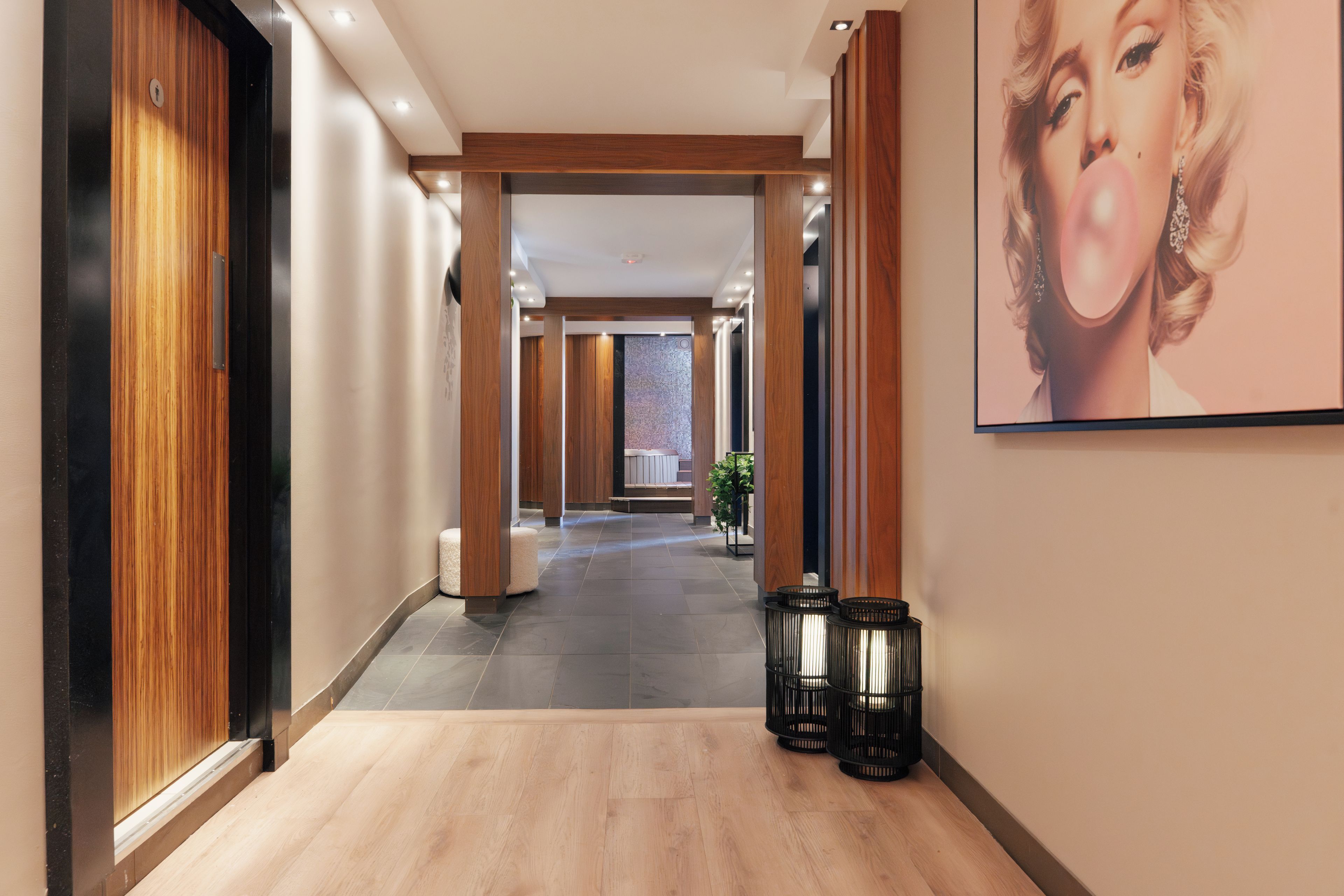 A hotel corridor with wooden paneling, a tiled floor, and a framed picture on the wall.
