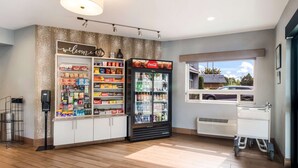 A clean, well-lit room with a Coca-Cola refrigerator, snack shelves, and a window with a view of a car outside. - Best Western McMinnville Inn (McMinnville)