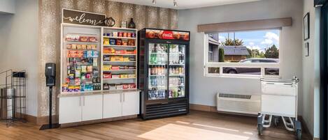Habitación limpia y bien iluminada con refrigerador Coca-Cola, estantes para snacks y una ventana que ofrece vistas de un coche fuera.