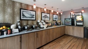 A modern kitchen with wooden cabinets, stainless steel appliances, and a variety of food items and condiments on the counter. - Best Western McMinnville Inn (McMinnville)