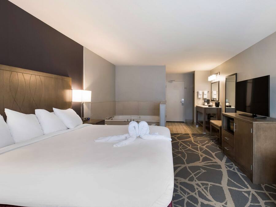 A hotel room with a large bed, a TV, a desk, and a bathroom.