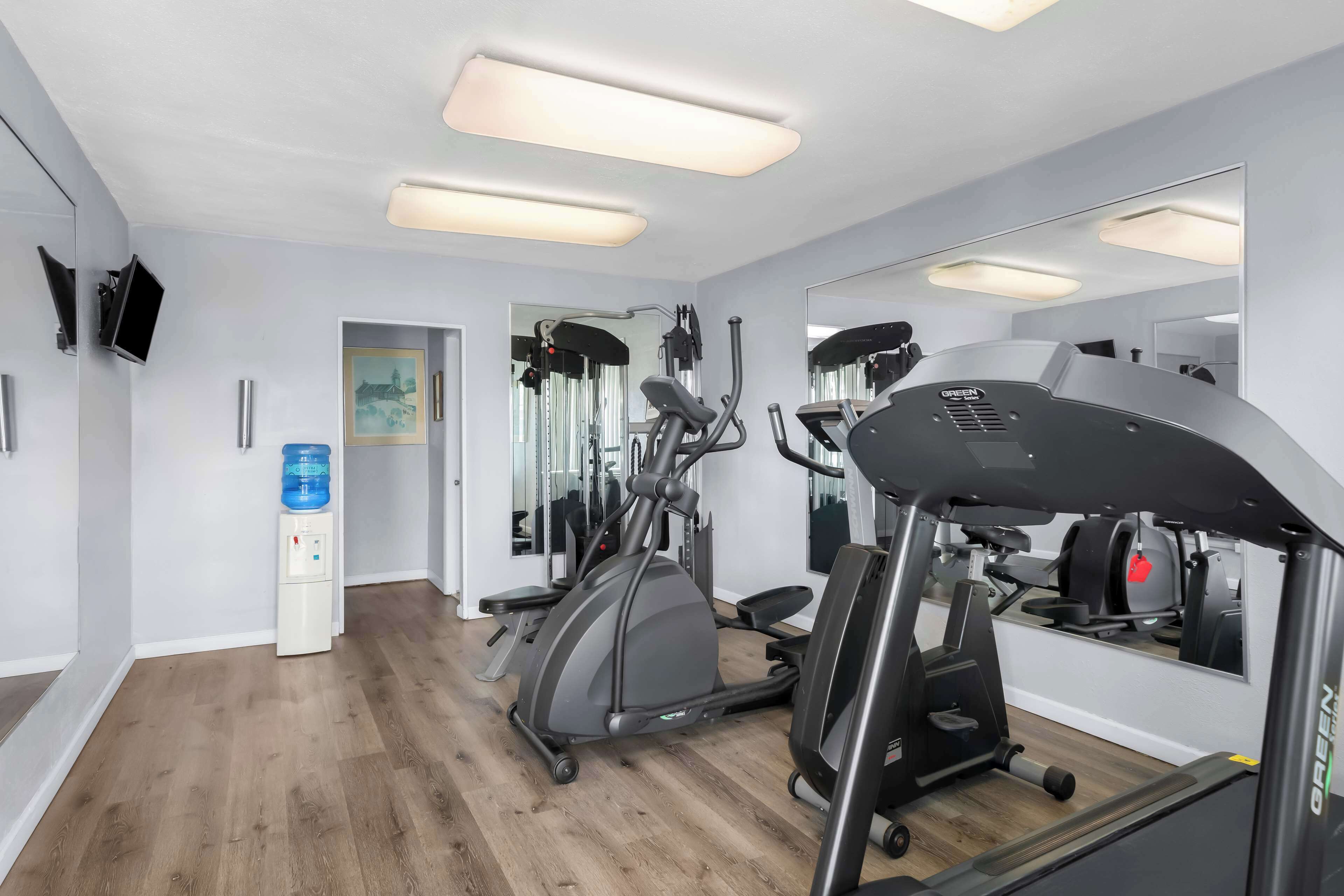 A gym with exercise equipment, a water dispenser, and a mirror.