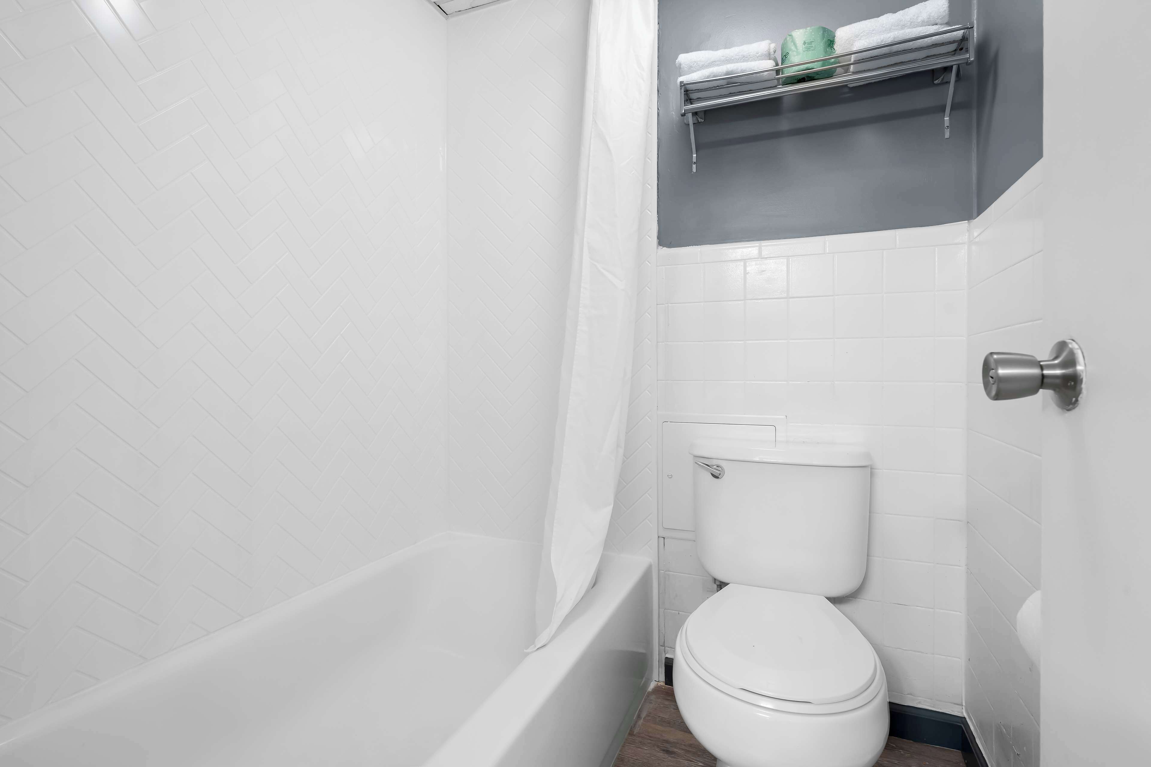 A bathroom with a white bathtub, a white toilet, and a shower curtain.