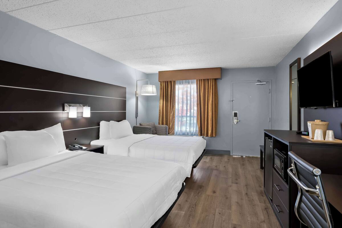 Une chambre d’hôtel avec deux lits, un bureau, une télévision et une salle de bain.