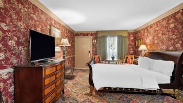 Een hotelkamer met een groot bed, een dressoir, een televisie en een raam met gordijnen.