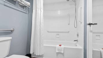 A modern bathroom with a white bathtub, a shower, and a toilet.
