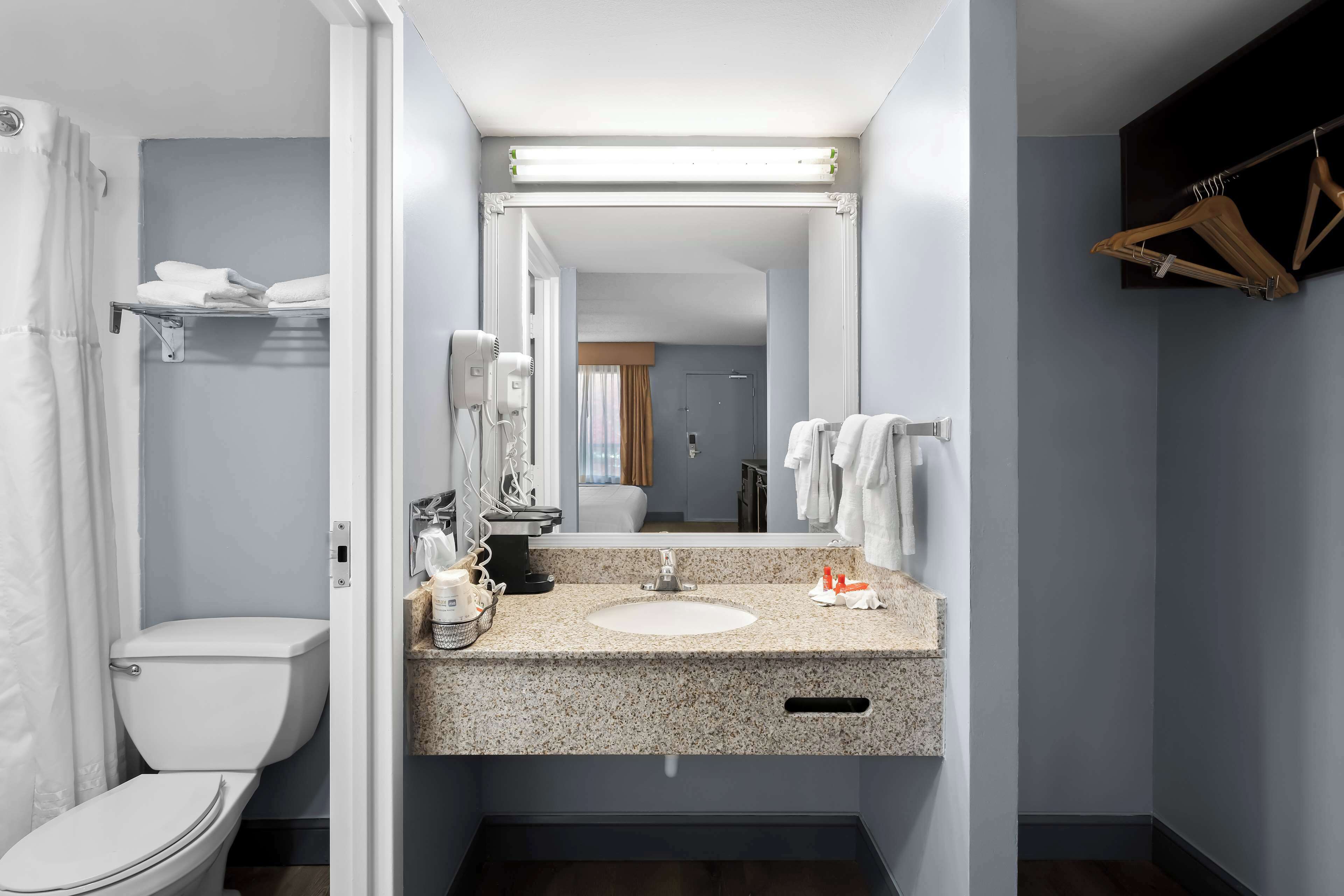 A modern bathroom with a granite countertop sink, a mirror above it, and a shower area with a curtain.