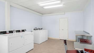 Uma lavanderia com máquina de lavar, secadora e uma mesa com cadeiras.