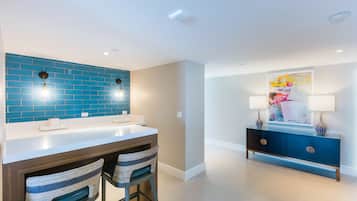 Een moderne keuken met blauwe tegels, een wit aanrecht en twee barkrukken.
