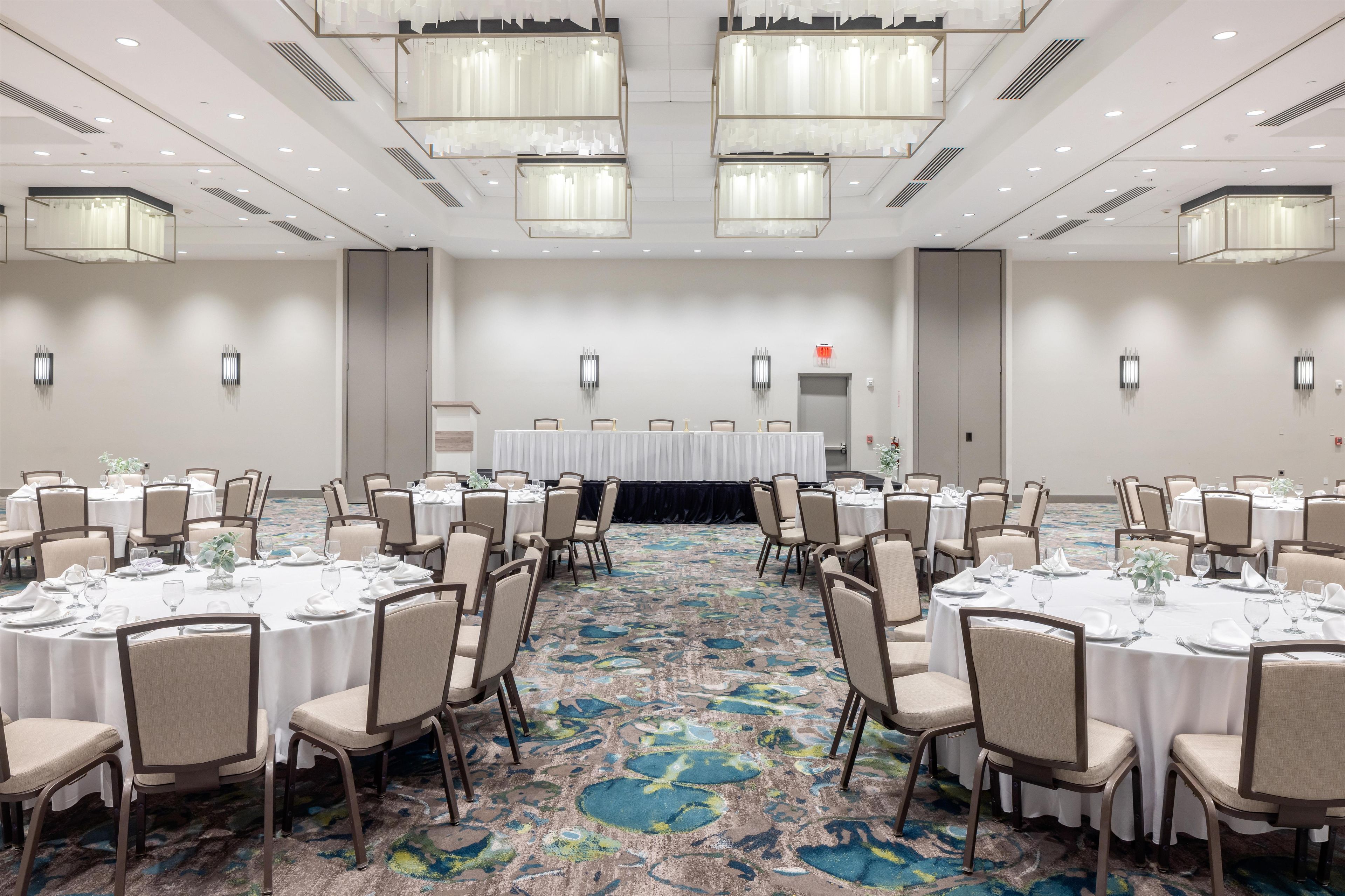 A conference room with round tables, chairs, and a carpeted floor.