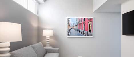 Een moderne woonkamer met een grijze bank, een ronde tafel met een boek, en een gekaderd stadsgezicht aan de muur.