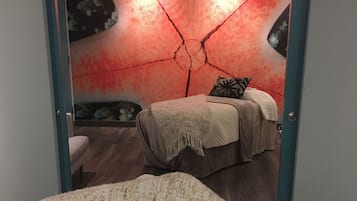 A bedroom with a bed, a bench, and a wall with a red design.