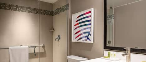 A modern bathroom with a glass shower enclosure, a white toilet, and a sink with a mirror.