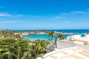 A resort with a pool, palm trees, and a view of the ocean. - Caribe Hilton (San Juan)