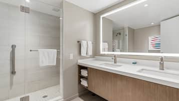 A modern bathroom with a glass shower enclosure, a large mirror, and a wooden vanity.