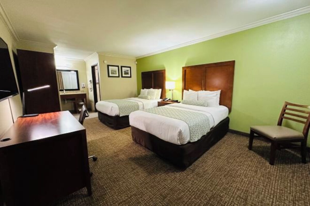 Une chambre d’hôtel avec deux lits, un bureau, une chaise et un téléviseur.