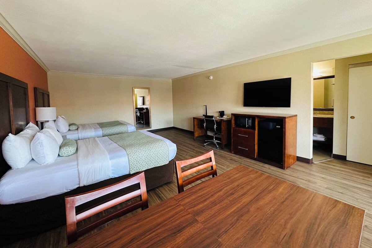 A hotel room with a bed, desk, chair, TV, and a mirror.