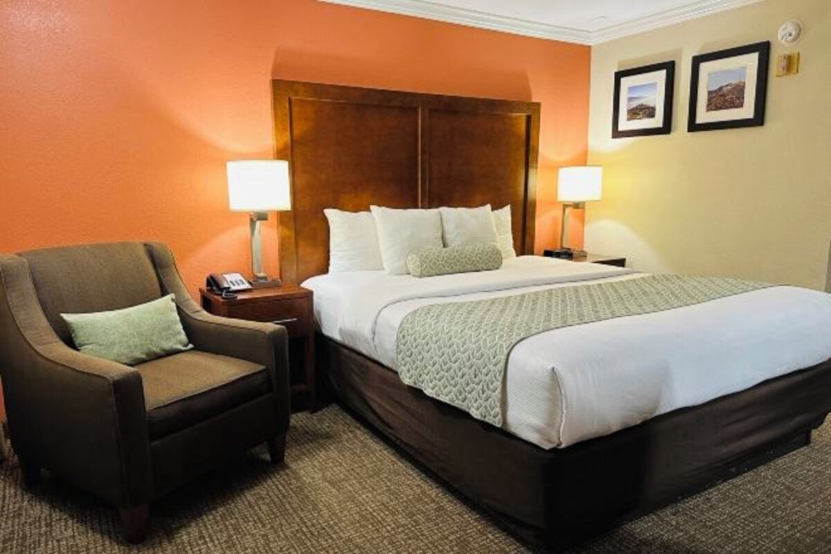 Une chambre d’hôtel avec un grand lit, deux tables de chevet, une chaise et deux lampes.