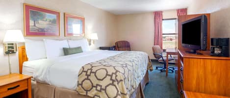 A hotel room with a large bed, a desk with a television, and two framed pictures on the wall.
