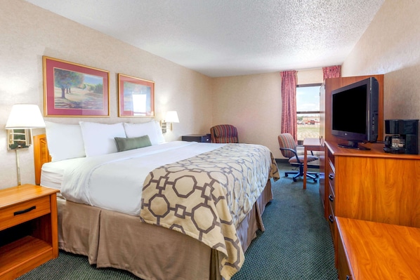 A hotel room with a large bed, a desk with a television, and two framed pictures on the wall. - Baymont by Wyndham Amarillo East (Amarillo)