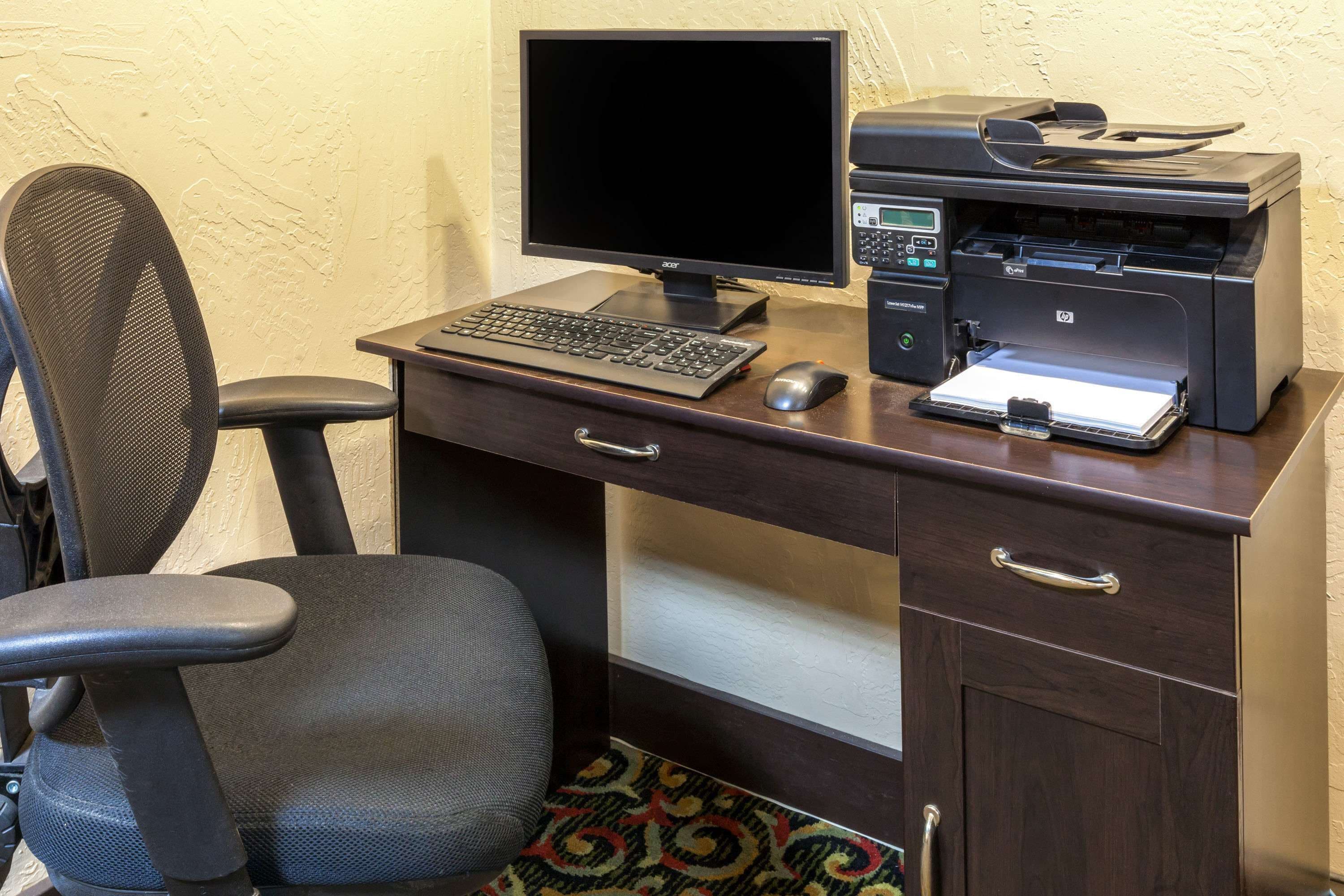 A desk with a computer, printer, and chair.