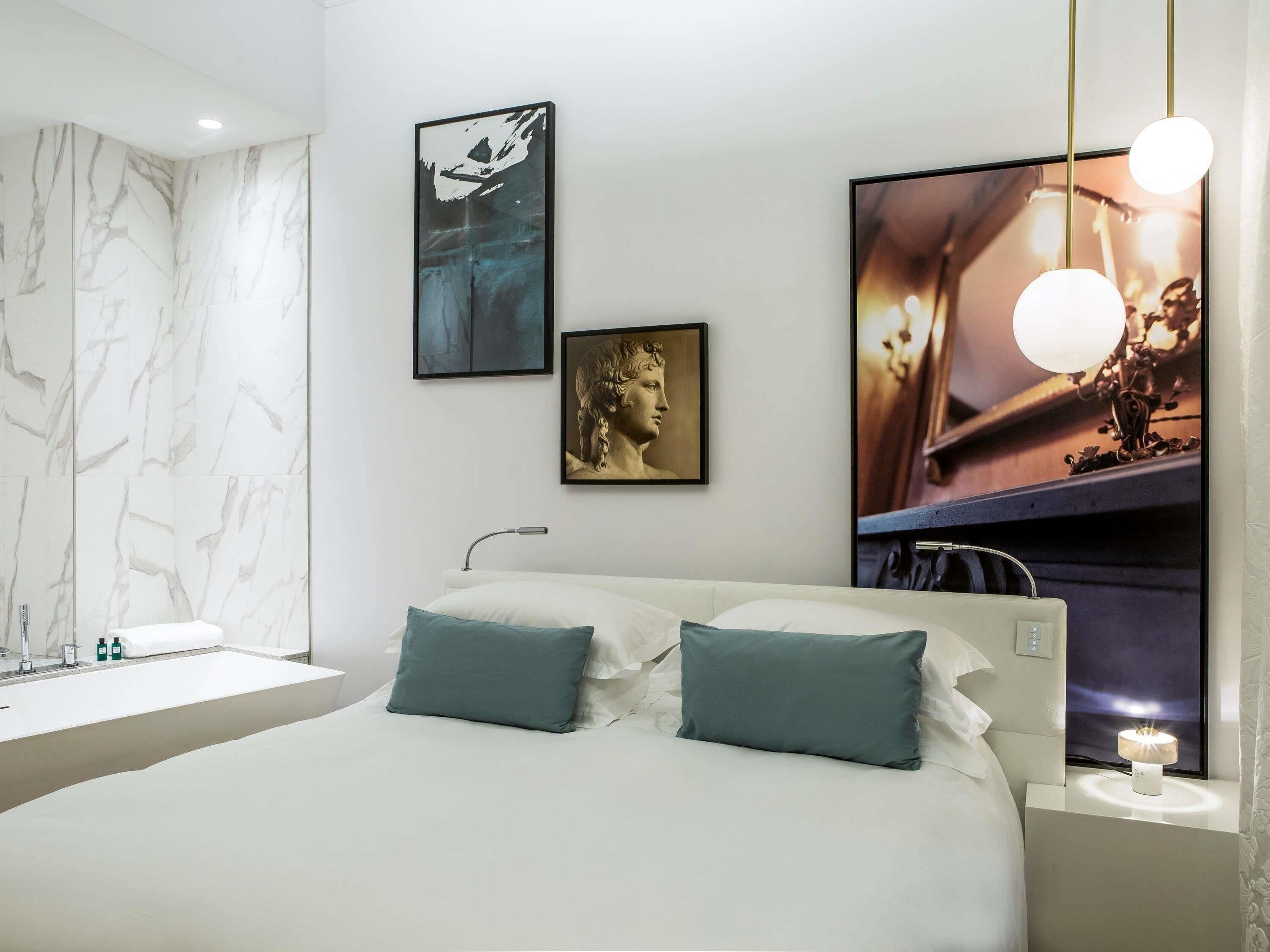 Una camera da letto moderna con una parete in marmo, un letto con due cuscini, un comodino con una lampada e un'opera d'arte appesa al muro.