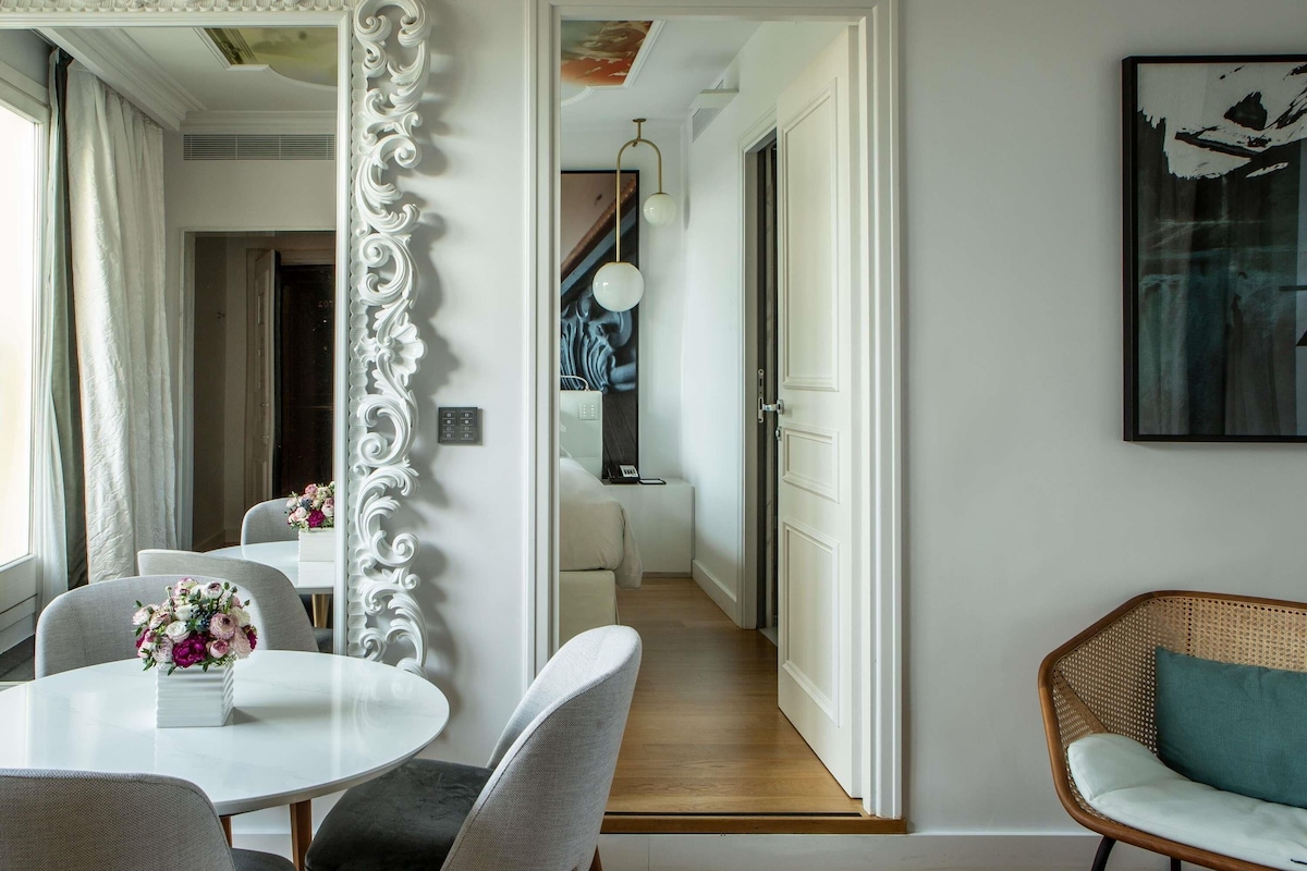 A modern interior with a dining area, a large mirror, and a staircase leading to another room.