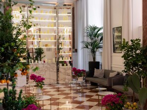 A lobby with a checkered floor, a sofa, a coffee table, and a large potted plant. - Sofitel Rome Villa Borghese (Rome)
