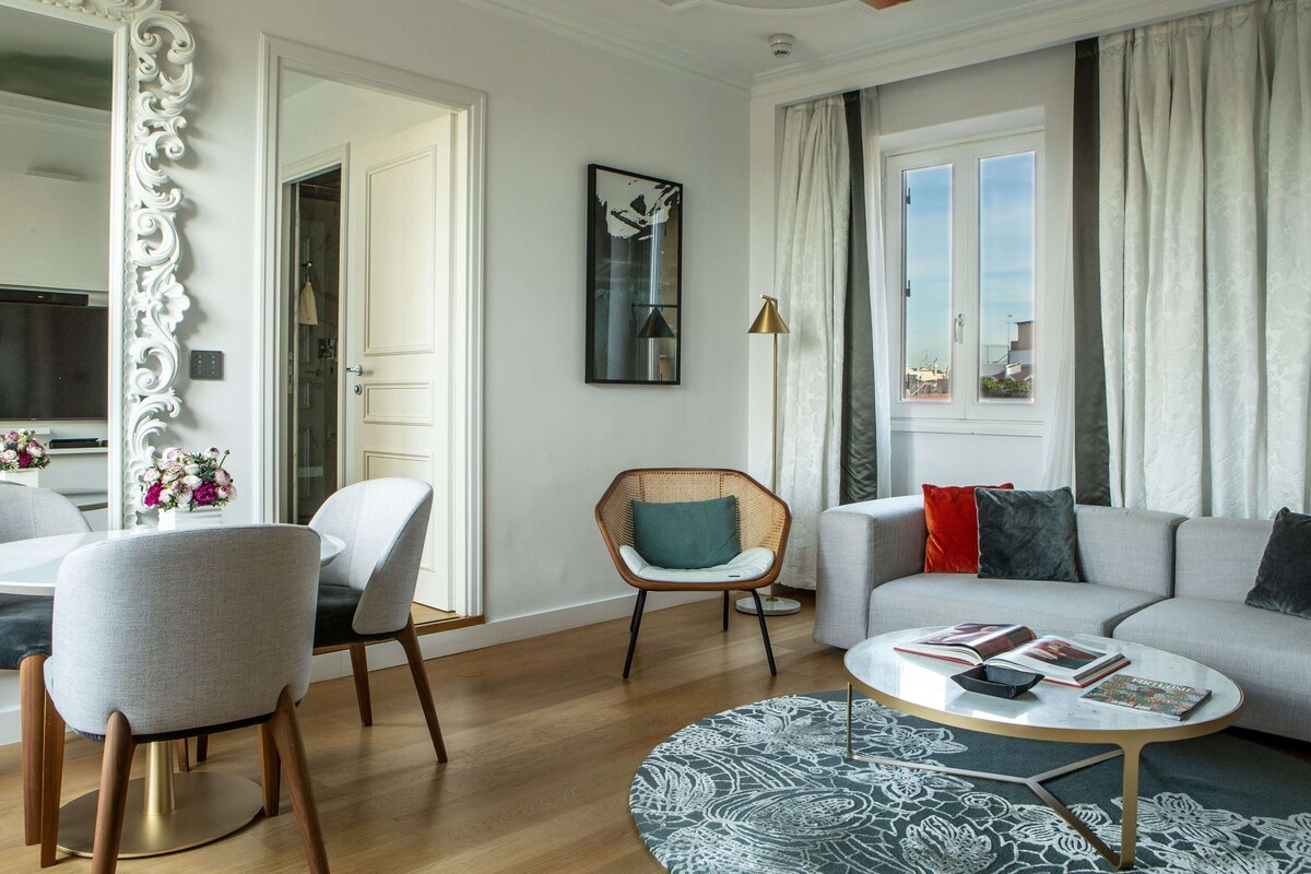 A modern living room with a round coffee table, a grey sofa, and a wicker chair.