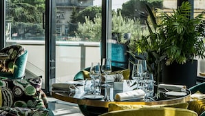 A dining area with a view of a historic building, a potted plant, and a table set for two. - Sofitel Rome Villa Borghese (Rome)