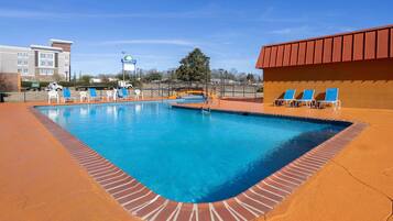 Relax by the pool surrounded by a brick walkway and lounge chairs.
