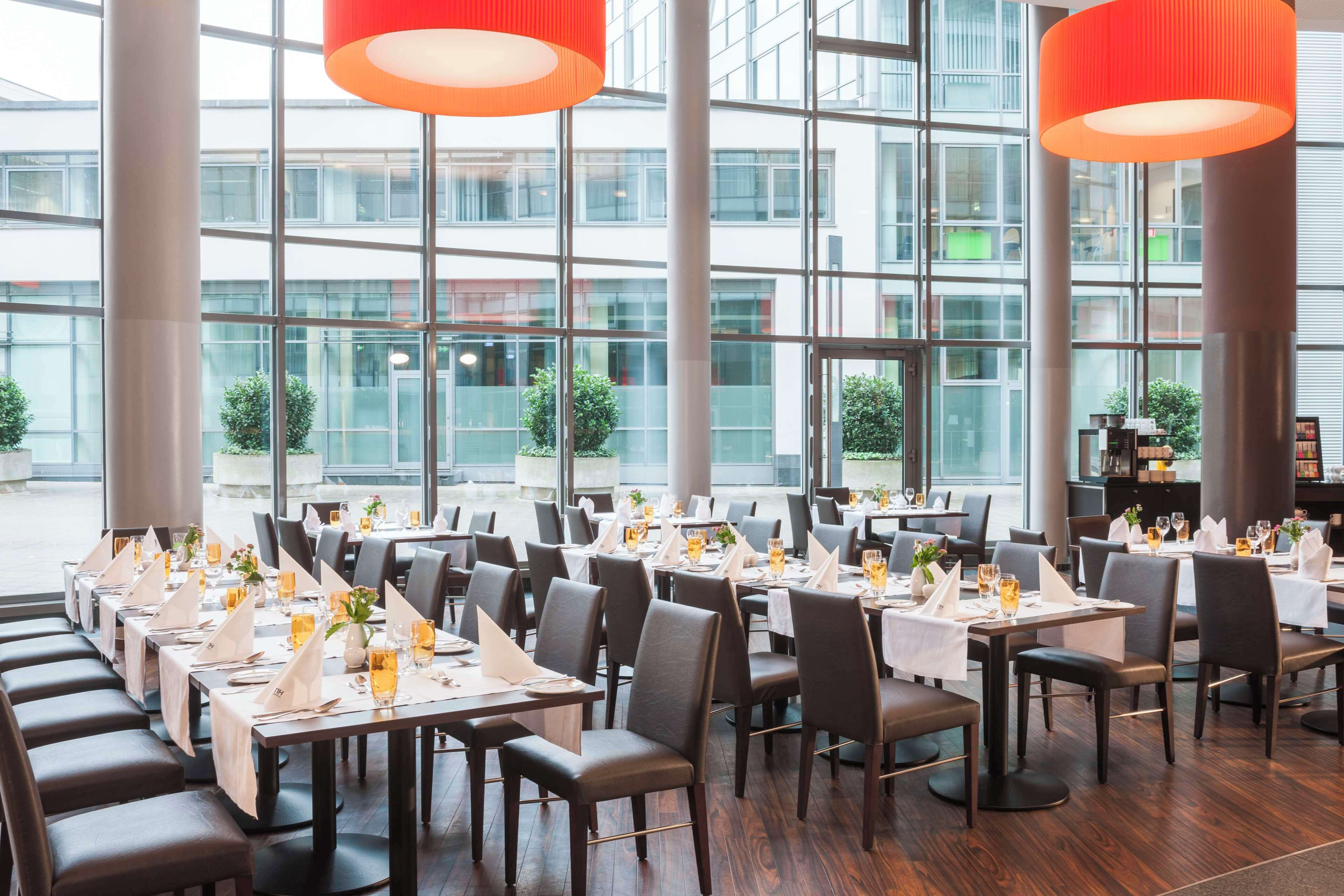 A restaurant with tables set for dining, large windows, and modern interior design.