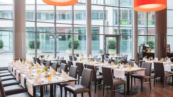 A restaurant with tables set for dining, large windows, and modern interior design.