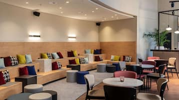 Ein moderner Lounge-Bereich mit Sitzgelegenheiten und Tischen, der verschiedene Farben und eine Wand aus Holz aufweist.