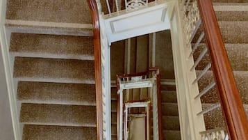 Una escalera con barandilla de madera y balaustres blancos, que conduce a un rellano con un panel decorativo en la pared.