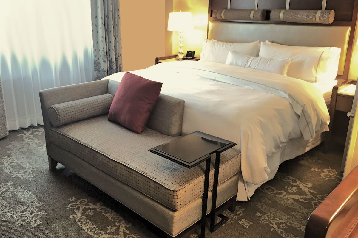 Ein Hotelzimmer mit Bett, einer Couch, einem kleinen Tisch und einer Lampe.