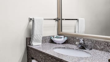 A bathroom with a granite countertop, a white sink, a mirror, and two towels hanging on a towel rack.