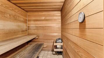 Un sauna avec des murs en bois, un banc, un appareil de chauffage et un thermomètre fixé au mur.