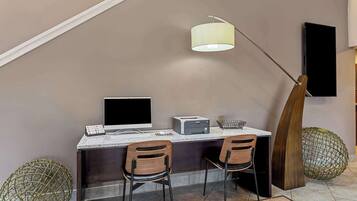 A modern workspace with a desk, two chairs, a computer, a printer, and a hanging lamp.