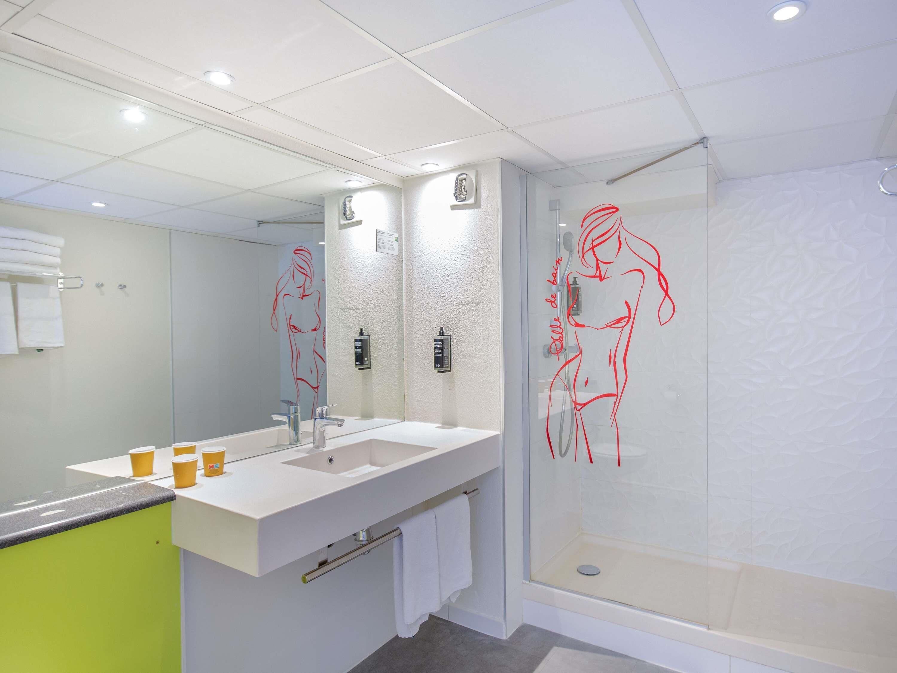 Un baño moderno con un espejo grande, un lavamanos y una zona de ducha.