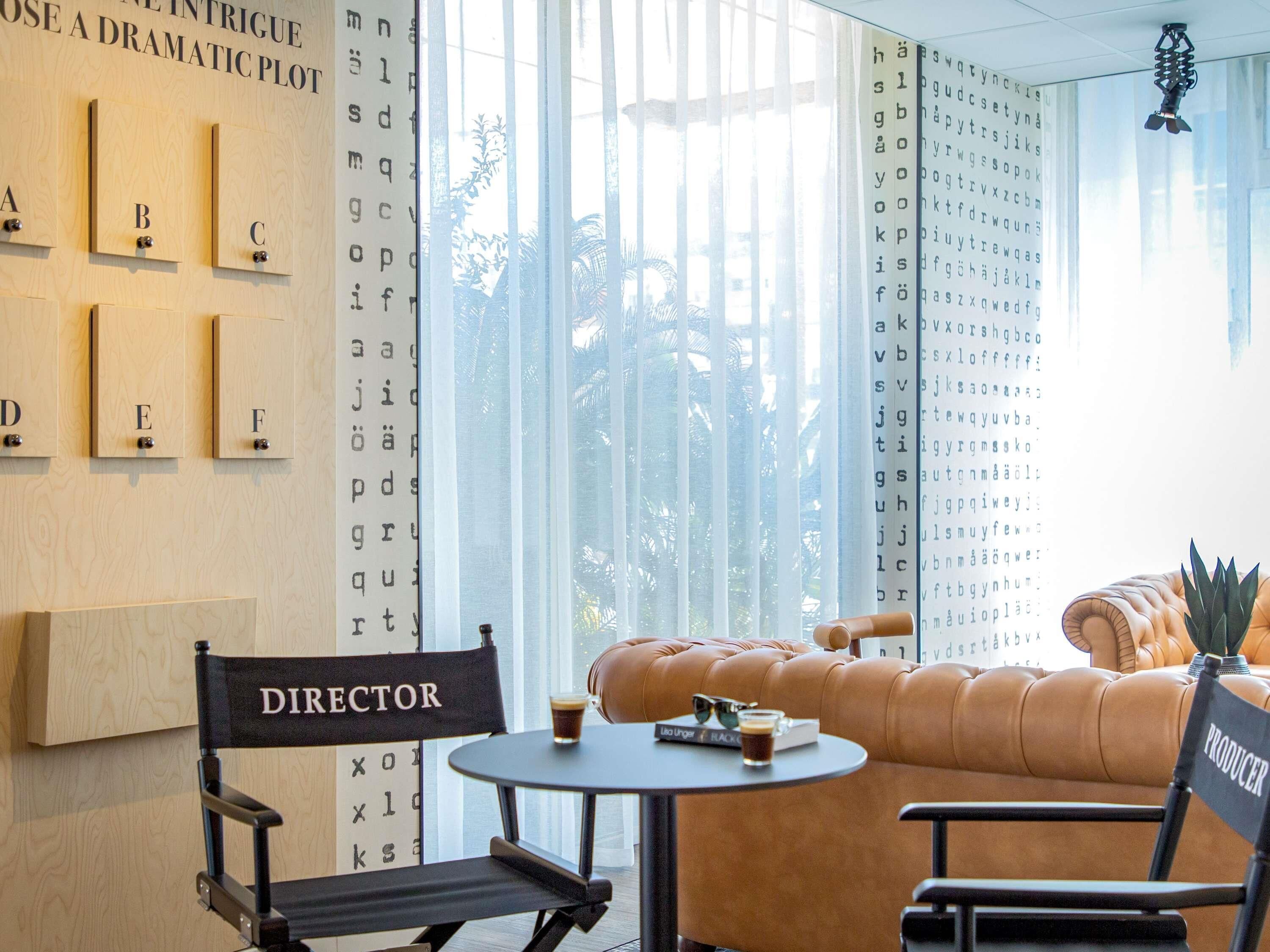 A modern interior with a director's chair, a sofa, and a table with a drink.
