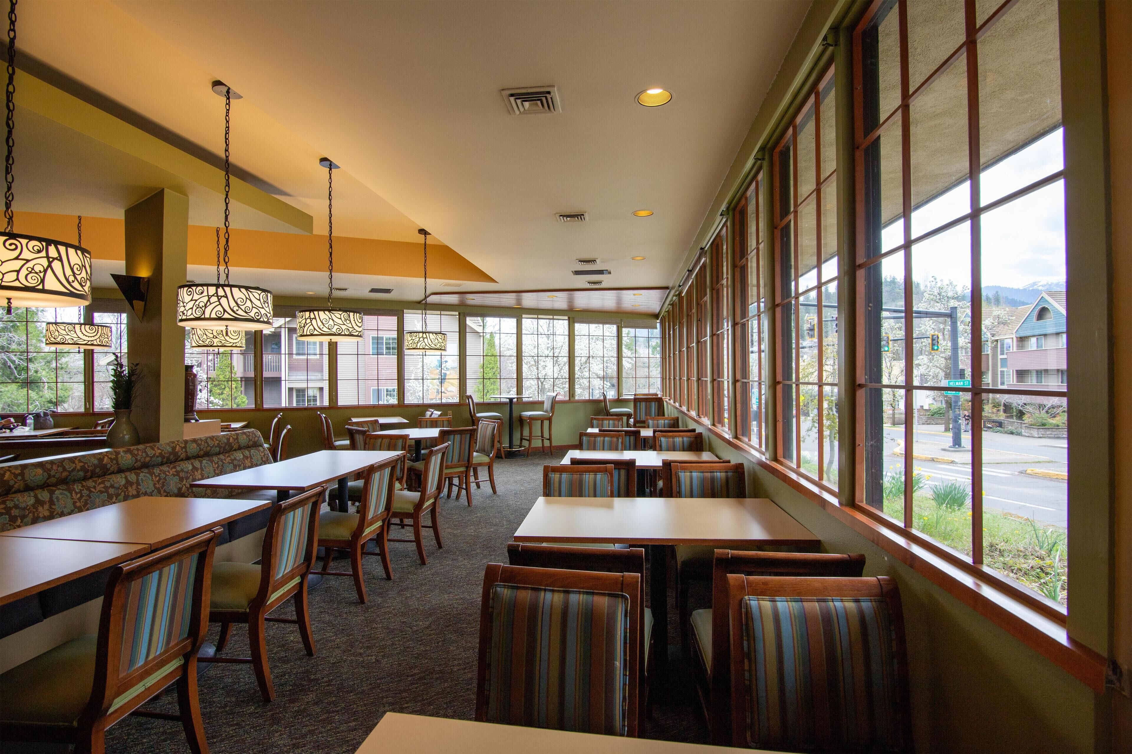 A restaurant with high ceilings, large windows, and a variety of seating options including booths and tables.
